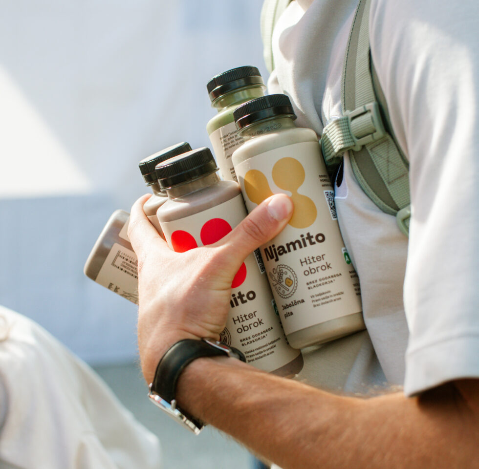 Young male holding bottles of healthy fast food.