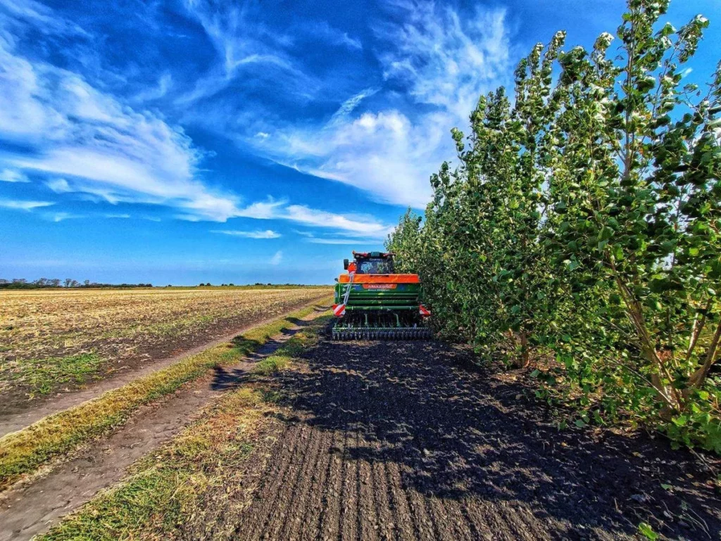 Tractor working on a filed next to trees that work as buffer zones.