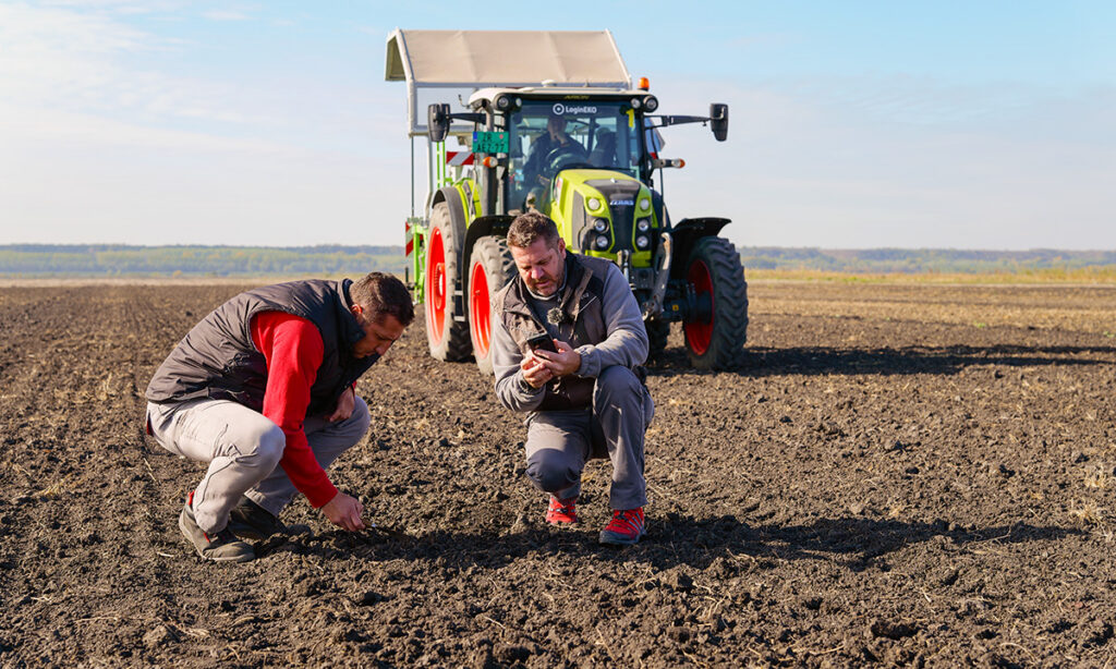 Operational team members reviewing data on a phone while out in a prepared agricultural field.